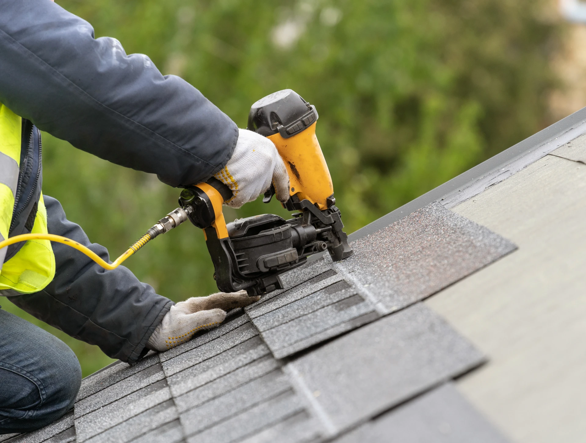 Worker securing roof shingles